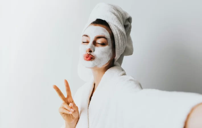 Woman applying facial oil drops onto her clean glowing skin as part of a nighttime skincare routine