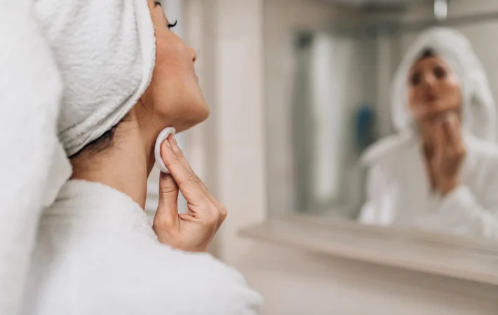 Woman applying night cream at 10 PM beside a clock showing the time with gentle evening lighting