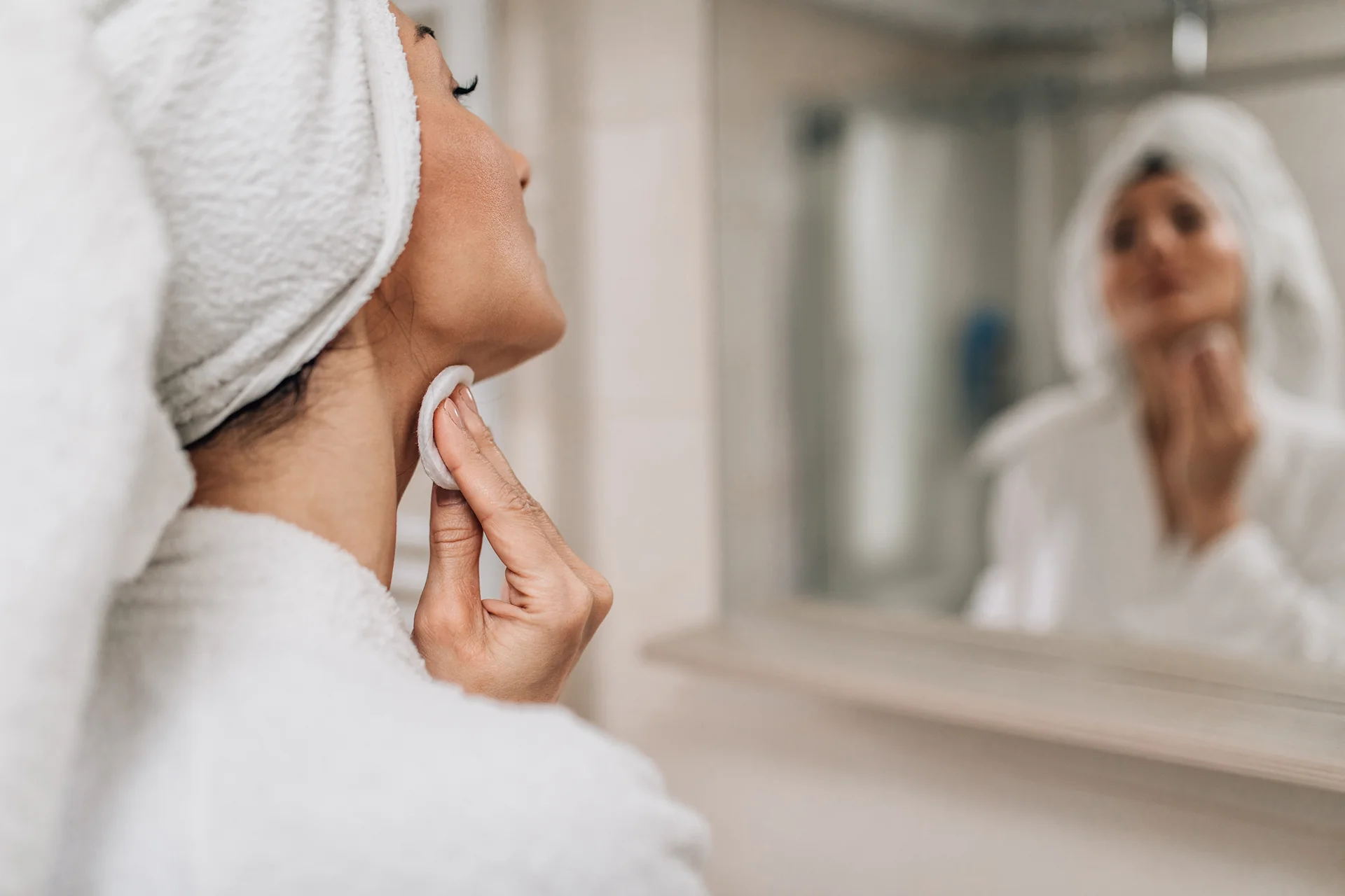 Woman applying night cream at 10 PM beside a clock showing the time with gentle evening lighting