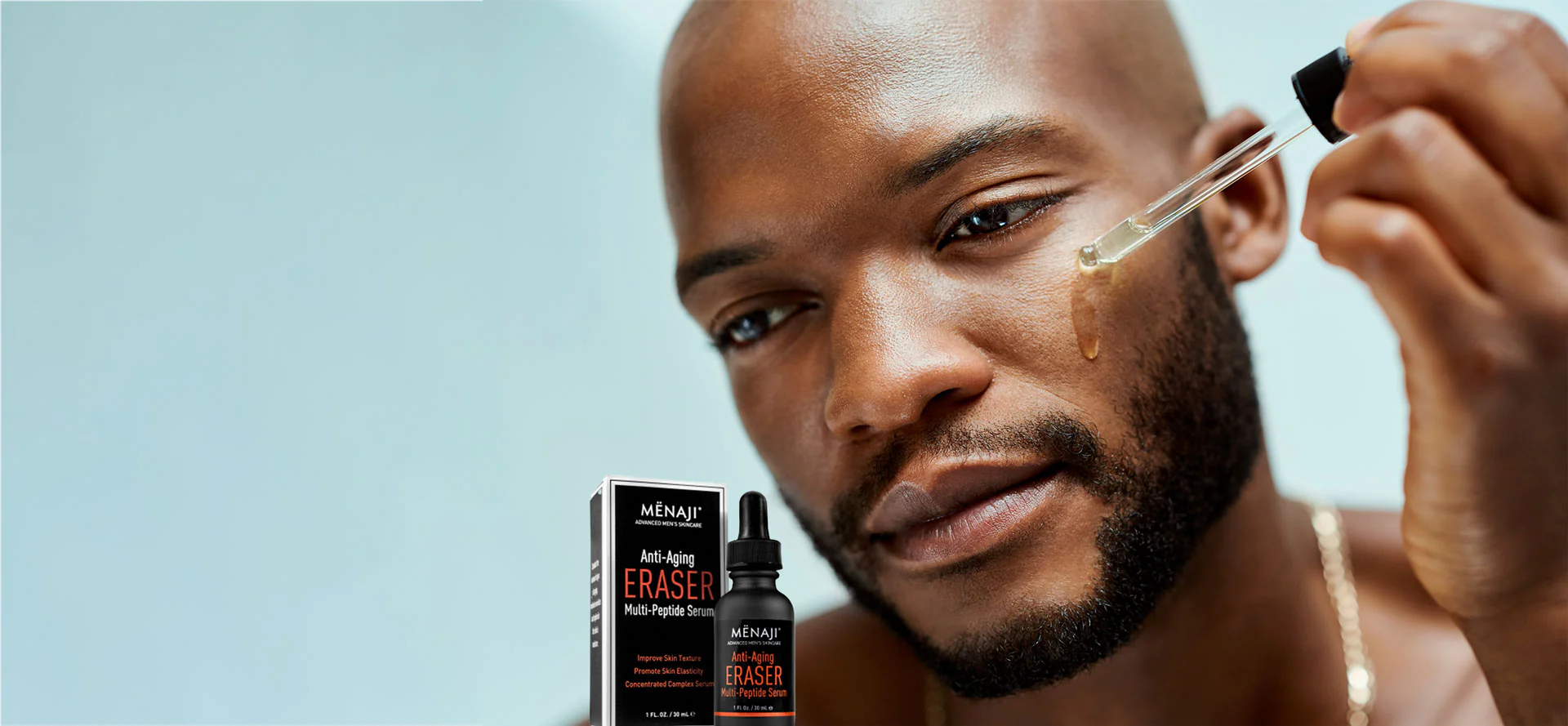 Man applying facial serum from dropper bottle in his morning skincare routine at bathroom sink